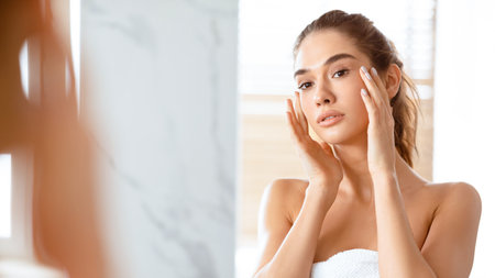 Young Woman Touching Face With Perfect Smooth Skin In Bathroomの写真素材