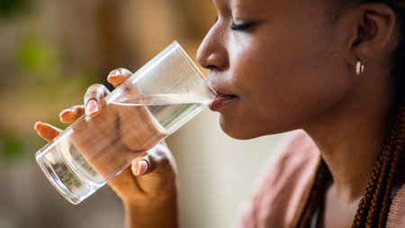 Closeup Shot Of Young Black Woman Drinking Mineral Water From Glassの写真素材