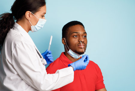 Doctor Making Covid-19 PCR Test For Male Patient, Blue Backgroundの写真素材