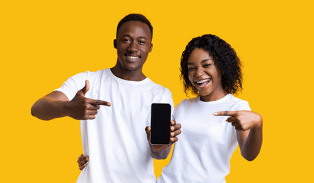 Cheerful black couple showing blank smartphone screen at camera