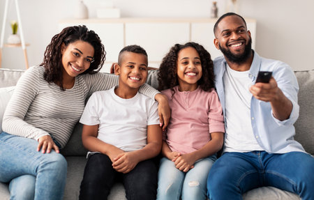 Happy young family watching television sitting on sofa