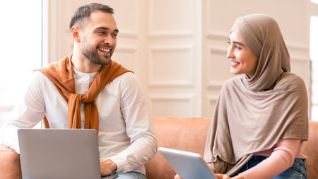 Young Muslim Couple Using Laptop And Tablet Sitting At Homeの写真素材