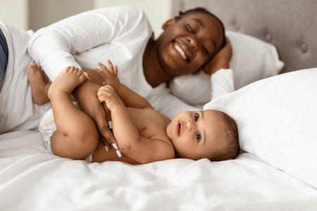African American mom lying in bed with her sweet babyの写真素材