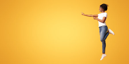 Happy young black woman jumping up and showing copy spaceの写真素材