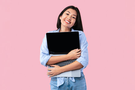 Excited asian woman hugging personal computer at studioの写真素材