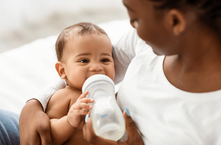 African American woman feeding her child from baby bottleの写真素材
