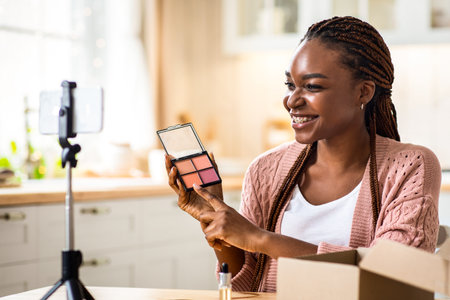 Beauty Blogging. Happy Young African Influencer Lady Recording Makeup Review In Kitchenの写真素材