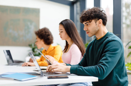 Multiracial male and female students studying for test, making homework with gadgets, focused guy...