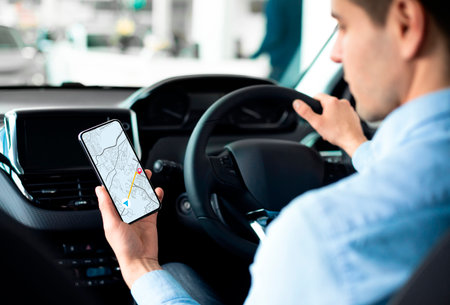 Young Man Using GPS Service Navigation App On Smartphone While Driving Car