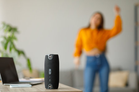 Young lady dancing to popular music at home, selective focus on portable wireless speaker, copy...