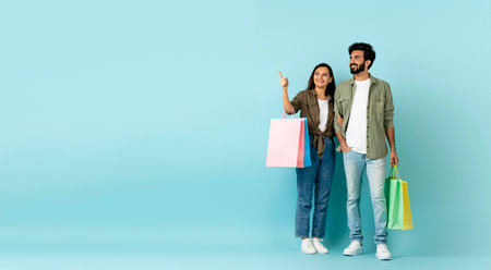 Loving multicultural couple go shopping together, copy space, carrying purchasesの写真素材