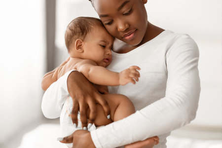 Portrait of black mother holding crying baby on handsの写真素材