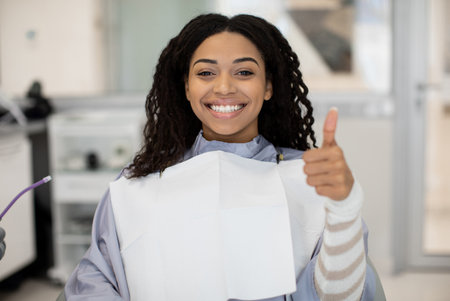 Smiling Black Female Patient Smiling And Showing Thumb Up After Dental Treatment