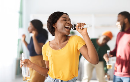Positive black lady with bottle of beer singing karaoke