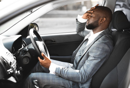 Exhausted african entrepreneur on a way home, driving car