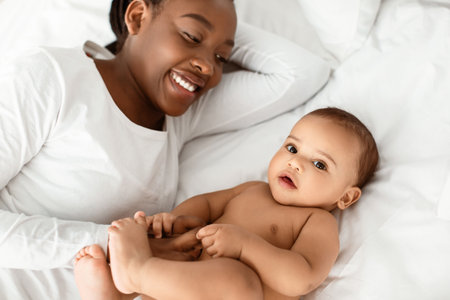 African American mom lying in bed with her cute infant