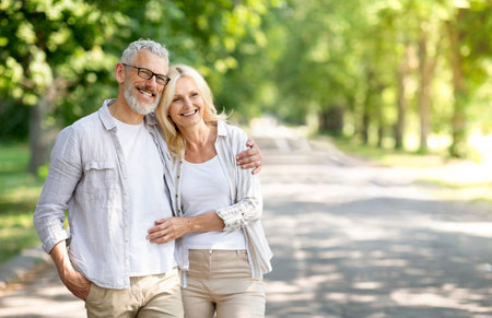 Beautiful mature spouses hugging outdoors while walking in summer parkの写真素材