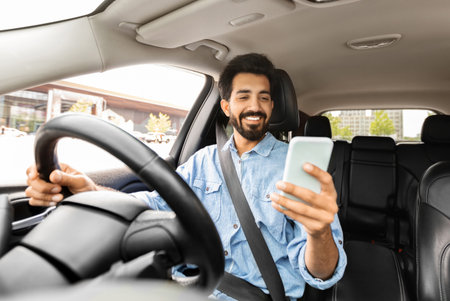 Cheerful indian man entrepreneur using cellphone while driving carの写真素材
