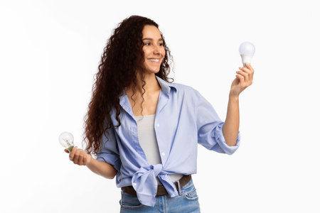 Cheerful Woman Holding Used Light Bulbs Standing Over White Backgroundの写真素材