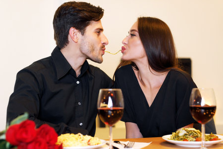 Smiling couple making spaghetti kiss together, celebratingの写真素材