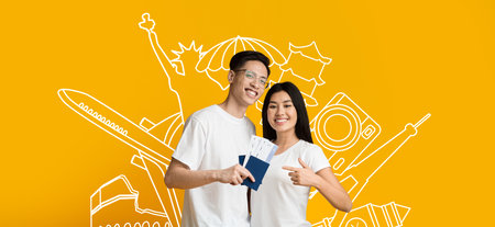 Couple excitedly showcases travel tickets against a vibrant yellow backgroundの写真素材