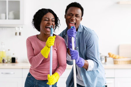 Positive black man and woman cleaning house and having funの写真素材
