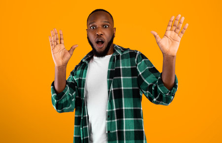 Shocked African American Guy Raising Hands Posing Over Yellow Backgroundの写真素材