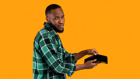 Poor African American Guy Showing Empty Wallet Over Yellow Background