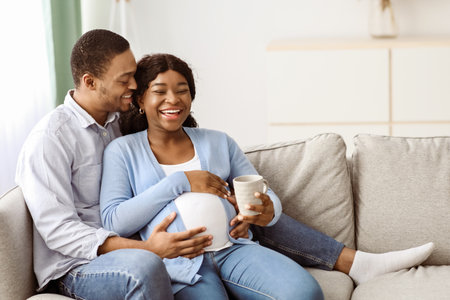 Loving husband kissing his laughing pregnant wife, home interiorの写真素材
