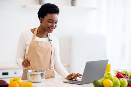 African Lady Cooking Using Laptop Browsing Recipes Online At Homeの写真素材
