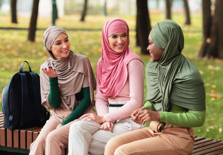 Three Modern Islamic Female Students Spending Time Chatting Outdoorsの写真素材