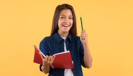 Teenage girl holding notebook and raising pen up at studioの写真素材