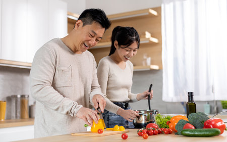 Attractive korean man and woman cooking together at homeの写真素材