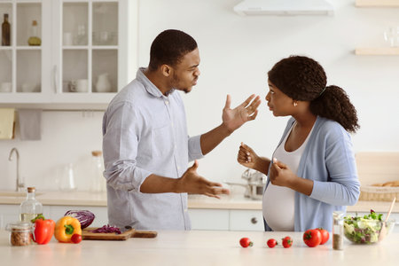 Pregnant woman fighting with her husband while cooking togetherの写真素材