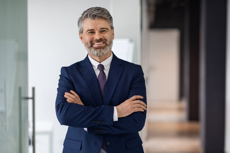 Portrait Of Handsome Middle Aged Businessman In Suit Standing With Folded Arms