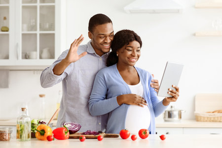 Positive expecting african couple having video call at kicthen