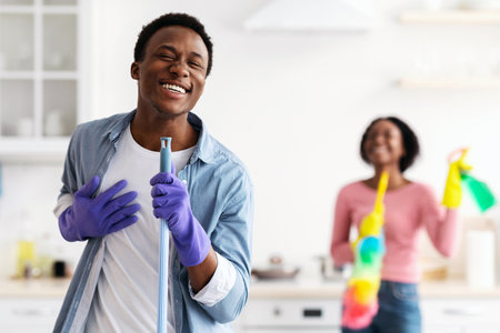 Black guy having fun with his girlfriend while cleaning kitchenの写真素材