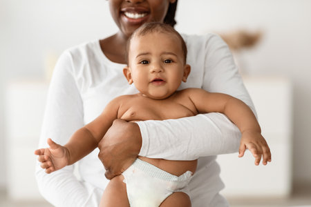 African American mom hugging her cute baby at homeの写真素材