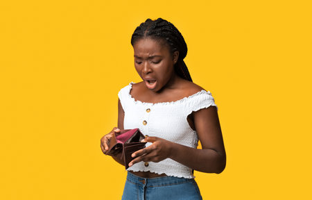 Poverty and absence of money. Shocked african american woman checking empty walletの写真素材