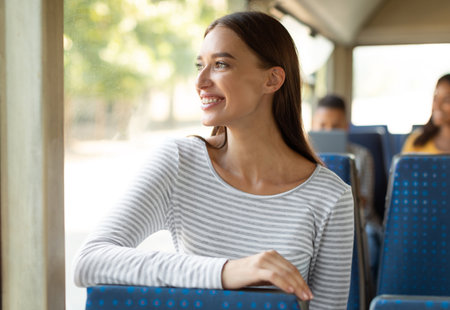 Smiling excited lady taking bus, looking at windowの写真素材