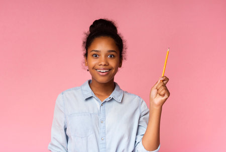 Teenage girl having idea, raising pencil in funny attention gestureの写真素材