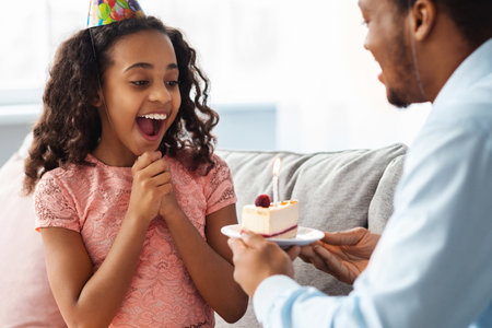 Surprised black girl looking at cake in father handsの写真素材