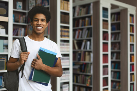 Handsome afro student posing on bookshelves background