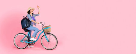 Excited asian woman riding retro bicycle with wicker basket