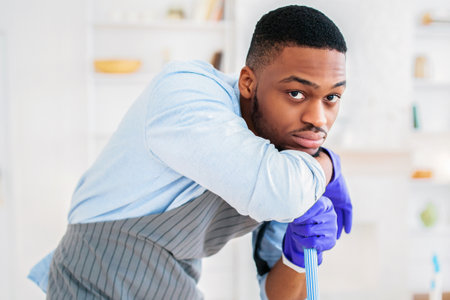 Millennial black guy feeling tired of too much domestic work, cleaning his apartment with his girlfriend, copy spaceの写真素材