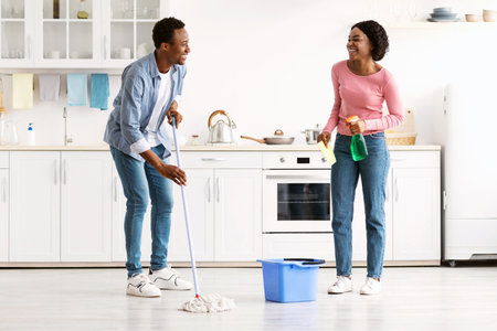 Beautiful black man and woman house-keepers cleaning kitchen