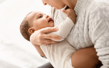 Young woman holding cute little African American infant on handsの写真素材