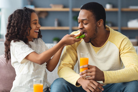 Cute little girl feeding her daddy at homeの写真素材