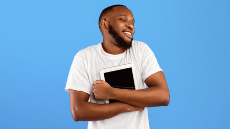 African American Guy Hugging Digital Tablet Over Blue Background, Panoramaの写真素材