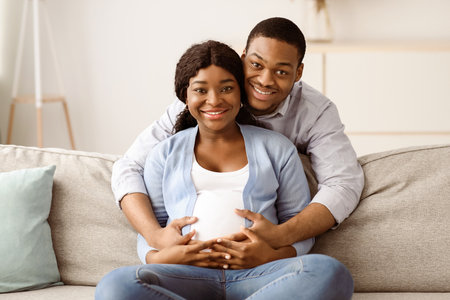 Happy expecting couple cuddling while spending time at homeの写真素材